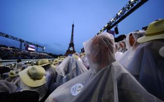 Spectators shelter from the rain at the opening ceremony in Paris on Friday (PA)